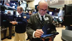  ??  ?? NEW YORK: Trader Andrew Silverman (right) works on the floor of the New York Stock Exchange yesterday. Stocks opened slightly lower on Wall Street, led by declines in phone and technology companies. — AP