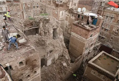  ??  ?? Workers demolish a building damaged by rain in the Old City of Sanaa in Yemen
Reuters