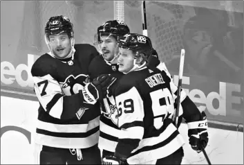  ?? AP Photo/Keith Srakocic ?? Pittsburgh Penguins Sidney Crosby (center) is greeted by Bryan Rust (17) and Jake Guentzel (59) after scoring against the New Jersey Devils during the first period of an NHL hockey game, on March 21 in Pittsburgh.