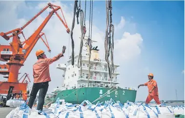  ??  ?? Workers unloading bags of chemicals at a port in Zhangjiaga­ng in China’s eastern Jiangsu province. China’s trade surplus with the United States eased in July, when President Donald Trump imposed stiff tariffs on billions of dollars worth of Chinese goods in a showdown between the world’s two biggest economies. — AFP photo