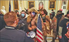  ?? (The New York Times/Erin Schaff) ?? Jacob Anthony Chansley (center), a QAnon adherent known as the Q Shaman, was identified in photos distribute­d widely and was taken into custody Saturday.