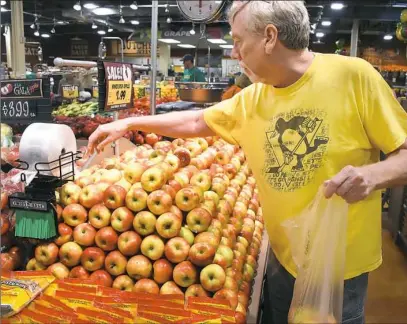  ??  ?? Robert Wells of Mt. Lebanon makes his selection of honeycrisp apples on Wednesday at Fresh Thyme Farmer’s Market in the Great Southern Shopping Center in Bridgevill­e.