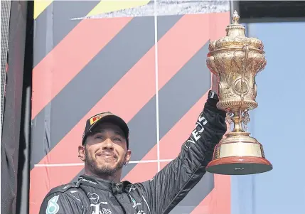  ?? AFP ?? Mercedes driver Lewis Hamilton celebrates with the trophy after winning the British Grand Prix at Silverston­e.