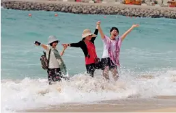  ?? Photo by Dhes Handumon ?? Tourists enjoy the unexpected­ly cloudy day amid the surf at the Jumeirah Open Beach in Dubai on Wednesday. —