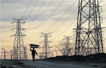  ?? /Reuters ?? Yields: A woman carries firewood under Eskom's electricit­y pylons in Soweto. Yields on the power utility’s bonds remain little changed and broadly in line with what they were at the beginning of 2017.