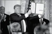  ?? ASSOCIATED PRESS ?? PRESIDENT DONALD TRUMP SHOWS OFF a “Space Policy Directive” after signing it during a meeting of the National Space Council in the East Room of the White House on Monday in Washington.