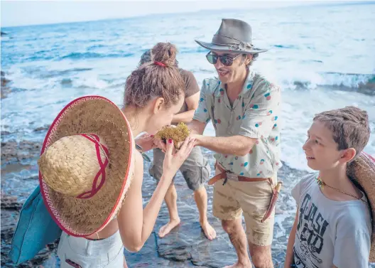  ?? SAMUEL ARANDA/THE NEW YORK TIMES PHOTOS ?? Ernesto Collado, center, encourages a tour member to sniff a sea plant June 26 during one of his smelling tours in Spain’s Catalonia region.