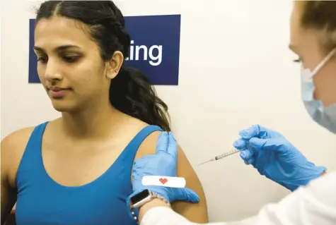  ?? ANTONIO PEREZ/CHICAGO TRIBUNE ?? Tanvi Nayak, 22, receives a bivalent COVID-19 booster shot from pharmacist Morgan Murphy at a CVS store in Chicago last fall.