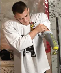 ??  ?? Hamilton Kilty B’s defenceman Josh Hampel uses screws to attach a hockey stick to his prosthetic lower left arm.