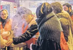  ??  ?? Give us your tired, your hungry: Volunteers give out meals to Syrian refugees and homeless women and men late last month in Istanbul, Turkey.