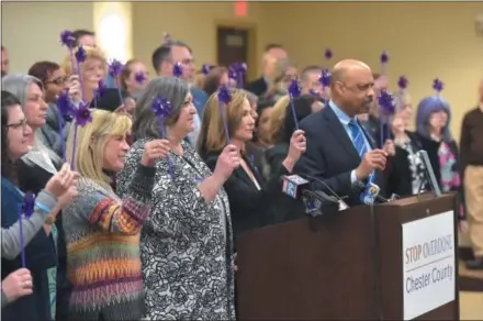  ?? PETE BANNAN — DIGITAL FIRST MEDIA ?? Chester County Commission­ers, center, Kathi Cozzone, Michelle Kichline and Terence Farrell, victims’ families and concerned community members and opioid awareness supporters hold purple pinwheels in a tribute to victims of the opioid crisis in Chester County.