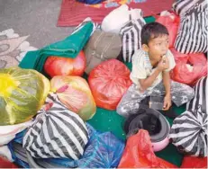  ?? — Reuters ?? A boy sits amongst his family belongings, after he was evacuated from a village located along the slopes of Mount Agung, at a temporary shelter in Rendang on the resort island of Bali on Saturday.