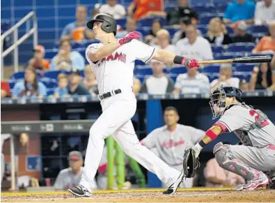  ?? WILFREDO LEE/AP ?? Miami infielder Tyler Moore hits a pinch-hit, three-run home run in the seventh inning against the Atlanta Braves on Sunday in Miami. The Marlins defeated the Braves, 3-1.