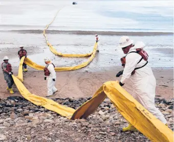  ?? JAE C. HONG/AP ?? A ruptured oil pipeline in 2015 polluted beaches in California’s worst coastal spill in decades. Above, workers prepare a containmen­t boom at Refugio State Beach.