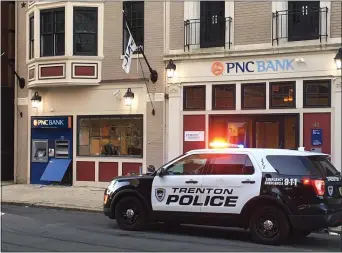  ?? L.A. PARKER/ TRENTONIAN PHOTO ?? Trenton police officer guards a PNC Bank and ATM on West State St. last week after people vandalized the building.