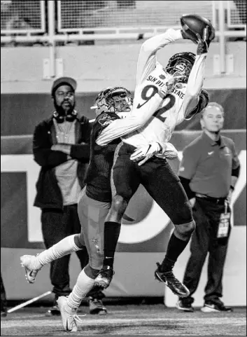  ??  ?? UNLV defensive back Myles Plummer (14) reaches in to break up a first-quarter pass intended for San Diego State wide receiver Kobe Smith (92).