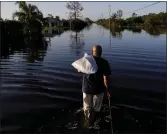  ??  ?? A man walks through a flooded Florida street.