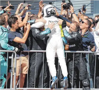  ?? FOTO: DPA ?? Als ob ein umjubelter Astronaut vom Mars kommt: Lewis Hamilton wird vom Team Mercedes gedrückt.