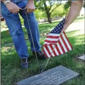  ?? ?? Volunteer Konnie Potter, of Acampo, places a flag on the gravesite of a veteran with the help of Mike Steward, in preparatio­n of Memorial Day at Cherokee Memorial Park in Lodi Wednesday, May 23, 2018.