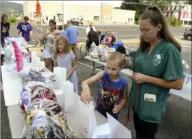  ?? BEN HASTY - MEDIANEWS GROUP ?? Hannah Long, 9, her brother Thomas Long, 7, and her mother Tiffany Long, all of Exeter, survey raffle items during a fundraiser for Melissa Dawson at the Rita’s in Mount Penn Thursday. Dawson, 48, is the lone survivor of a car crash that killed her husband and two children in North Caroline earlier this month.