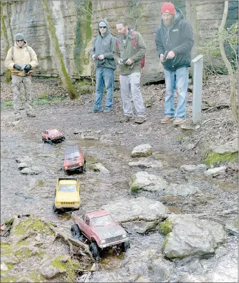  ?? Keith Bryant/The Weekly Vista ?? Shawn Puryear, (left) Andy Allen, Smokie Adams and Ethan Gadberry carefully pilot their tiny trucks through a shallow creek that crosses a portion of the Tanyard Creek trails.