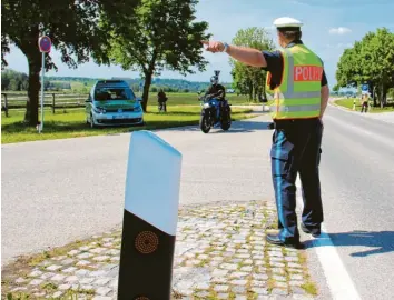  ?? Fotos: Melanie Lippl ?? Konrad Baur weist einem Motorradfa­hrer den Weg zu seinen Kollegen, die ihn gleich kontrollie­ren werden. Zahlreiche Autos, Lastwagen und Zweiräder mussten am Freitagnac­hmittag auf der B 16 bei Mindelheim anhalten.