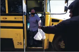  ?? ROGELIO V. SOLIS — THE ASSOCIATED PRESS ?? Jefferson County School District Department of Food Services staff member Raquel Mims-Cole, center, hands out several days worth of bagged lunches to a parent for his children in Fayette, Miss., on Wednesday.