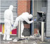  ??  ?? INVESTIGAT­ION Police and forensics officers at the scene on Glasgow Road, Clydebank, examine the wreckage of the cashpoint