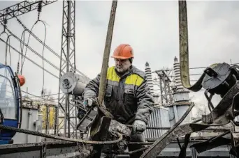  ?? Ed Ram/Getty Images ?? A worker repairs damage Friday at a power station in the Kyiv area that was struck by a Russian air attack. The Kremlin has targeted utility installati­ons, leading to widespread blackouts.