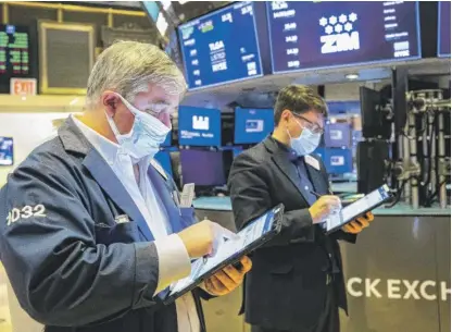  ?? COLIN ZIEMER/NEW YORK STOCK EXCHANGE VIA AP ?? A pair of traders work at the New York Stock Exchange last week. One worrisome trend for market observers is that stock prices have been soaring at a much faster pace than corporate profits.