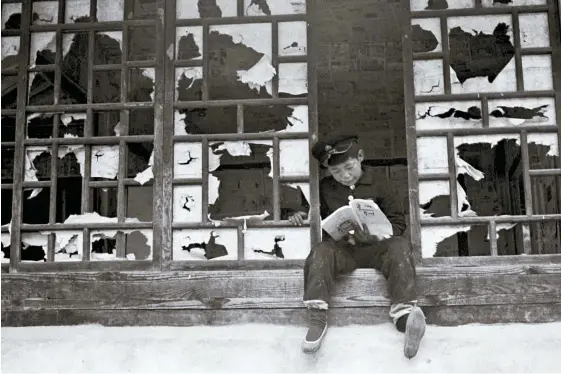  ?? Courtesy of Noonbit Publishing ?? A schoolboy in uniform reads a textbook at a traditiona­l Korean house with torn paper in the windows. This photo is one of hundreds of images published in Hwang Gyu-tae’s recently published photobook, “Before Blowing Up.” HIs photos were taken between 1958 and 1964.