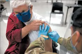  ?? ERIN HOOLEY/CHICAGO TRIBUNE ?? Gerald Lewis, 82, gets a COVID-19 vaccine Thursday at Triton College in River Grove. The Illinois National Guard helped Cook County set up a mass vaccinatio­n site there.