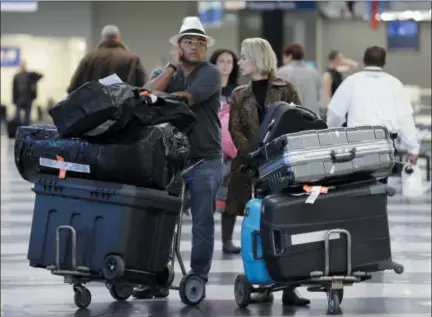  ?? THE ASSOCIATED PRESS FILE PHOTO ?? Travelers walk through baggage claim at O’Hare Internatio­nal airport in Chicago, Ill. More people than ever before are buying travel insurance to protect their vacations. So far this year, AAA’s domestic and internatio­nal travel insurance sales are up 20 percent over the same period last year. According to a recent AAA travel survey, nearly four in 10 Americans — or 38 percent — are likely to purchase insurance for internatio­nal trips.