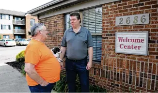  ?? MARSHALL GORBY / STAFF ?? Cobblegate Square Apartments property manager Dave Cook (right) talks with resident Larry May, who his holding his dog, Panda, on June 17 in Moraine.