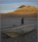  ?? JOHN LOCHER — THE ASSOCIATED PRESS ?? Misha McBride looks at a formerly sunken boat now on cracked earth hundreds of feet from what is now the shoreline on Lake Mead on Monday near Boulder City, Nev.