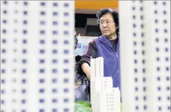  ?? ZHU XINGXIN / CHINA DAILY ?? A visitor examines a property project model at a real estate expo in Beijing. Wang Tao, the year-on-year slump in Shanghai home sales volumes in October