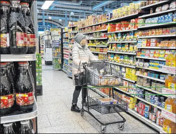  ?? Nam Y. Huh The Associated Press ?? A customer checks prices while shopping Friday at a grocery store in Wheeling, Ill. A typical basket of groceries now costs 20 percent more than in February 2021.