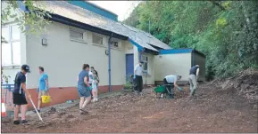  ?? 01_B35BPS01 and 01_B35BPS02 ?? Volunteers rake and unearth stones which other volunteers cart away in wheelbarro­ws until the outdoor area nears the stage where grass seed can be sown.