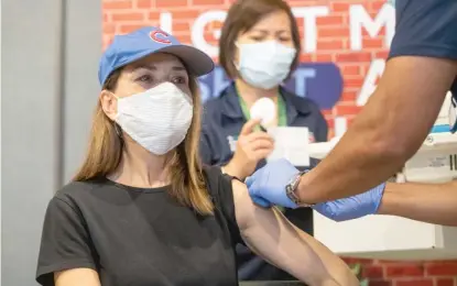  ?? TYLER LARIVIERE/SUN-TIMES ?? Karen Jozefowicz receives her first dose of the Pfizer COVID-19 vaccine Monday on the opening day of a mass vaccinatio­n site at Gallagher Way next to Wrigley Field.