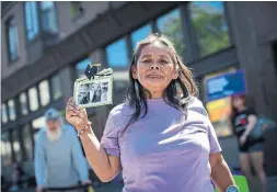  ?? DARRYL DYCK THE CANADIAN PRESS ?? Laura Pierre holds up a photograph that includes friends Arthur Lakis and a man named Johnny who died last year during a memorial march to remember victims of overdose deaths in Vancouver in August.