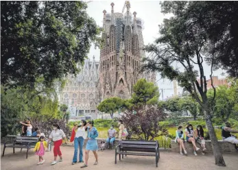  ?? FOTO: EMILIO MORENATTI/DPA ?? Passanten stehen in einem Park der Basilika „Sagrada Familia“in Barcelona. Auch für Katalonien hat das deutsche Außenminis­terium jetzt eine Reisewarnu­ng herausgege­ben.