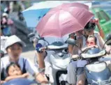  ?? HUANG SHIPENG / FOR CHINA DAILY ?? Commuters try to shield themselves from the sun in Huaibei, Anhui province, on Sunday, when Anhui issued an orange alert for heat. Temperatur­es across the province soared at 37 to 39 C and in some areas up to 40 C.
