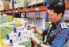  ??  ?? PEGAWAI penguat kuasa KPDNKK memeriksa barangan tiruan yang dirampas di Jalan Petaling.