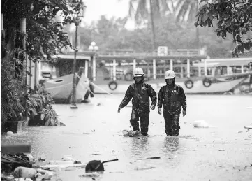  ??  ?? Electric workers wade through a flooded street in the town of Hoi An following days of heavy rains after Typhoon Damrey hit the coast. — AFP photo