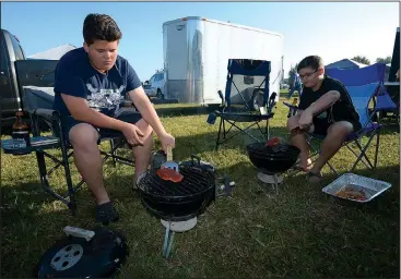  ?? NWA Democrat-Gazette/ANDY SHUPE ?? Brett Backerman, 13, (left) and his brother, Cole Backerman, 11, turn their boneless pork tenderloin­s on their grills Saturday during a Kids Q, a barbecue competitio­n for children, as a part of the Bikes, Blues &amp; BBQ motorcycle rally at the Washington County Fairground­s in Fayettevil­le.