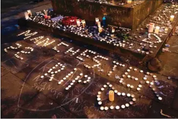  ?? JON SUPER/AFP ?? Memorial candles are seen during a vigil on St Ann’s Square in Manchester, England, on Monday.