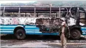  ??  ?? Police personnel walks infront of a charred bus burnt down by bandh supporters of United Naga Council, at Senapati, Manipur on Monday