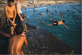  ?? (AP/Khalil Hamra) ?? Palestinia­ns jump into the water Aug. 6 as they enjoy a summer day on the beach of Gaza City.