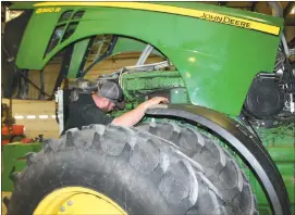  ?? Mona Weatherly ?? Above, Kyle Finney works on the dampener of the engine on a John Deere 8360 R tractor.