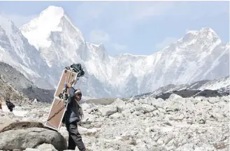  ??  ?? A porter carries crates containing oxygen tanks on his way to Everest Base Camp, at Lobuche, Nepal. A Nepalese official says Sherpa workers are fixing the final route to the summit of Mount Everest and the first climb of the season could be Sunday.